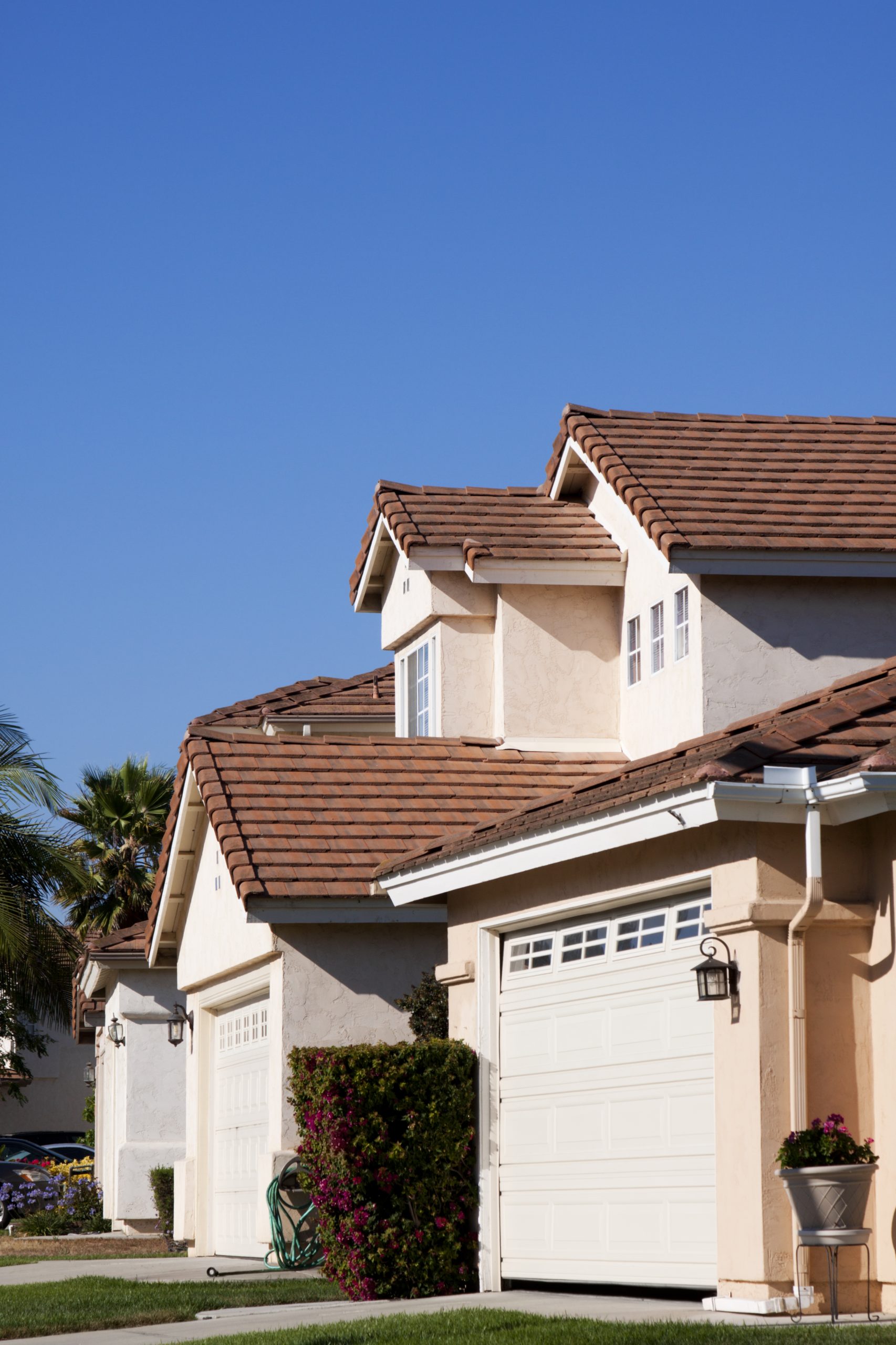 Neighborhood Stucco Home Exterior and Blue Sky Tile Roofing.